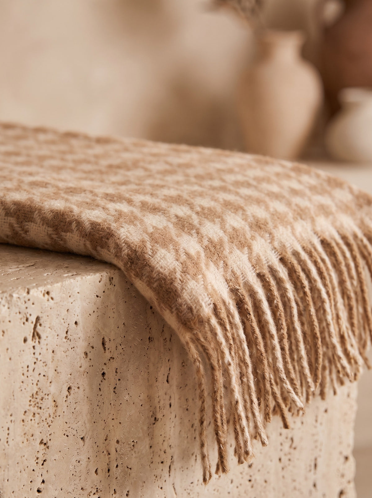 Close-up of the brushed houndstooth weave and fringed end of the camel scarf
