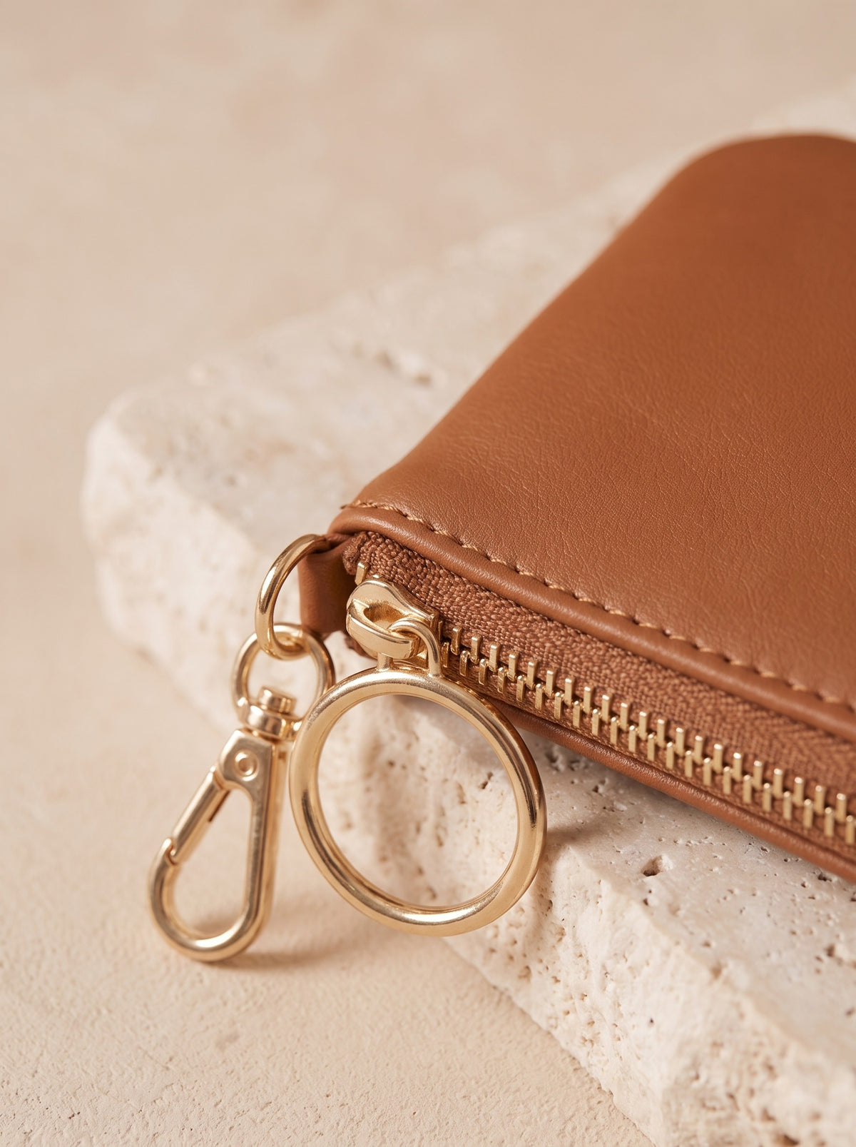 Close-up of the gold-tone zip and ring pull of the cognac Mini Zip Coin Purse