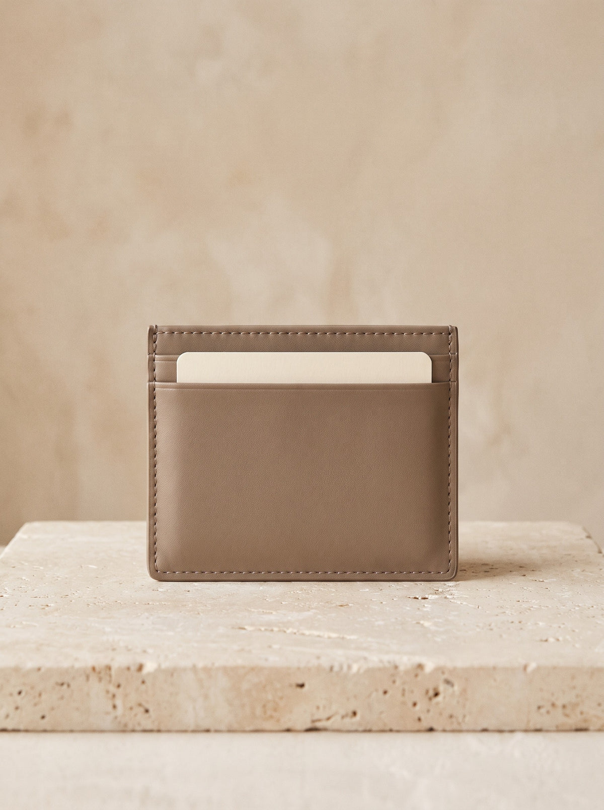 Slim Card Holder in taupe vegan leather on a pale travertine block