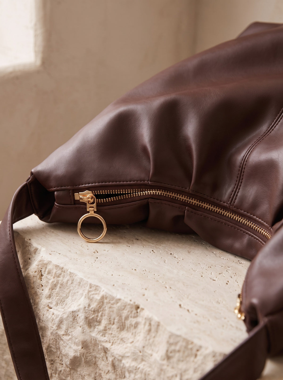 Close-up of the soft folds and gold-tone zip pull of the chocolate Slouch Hobo Bag
