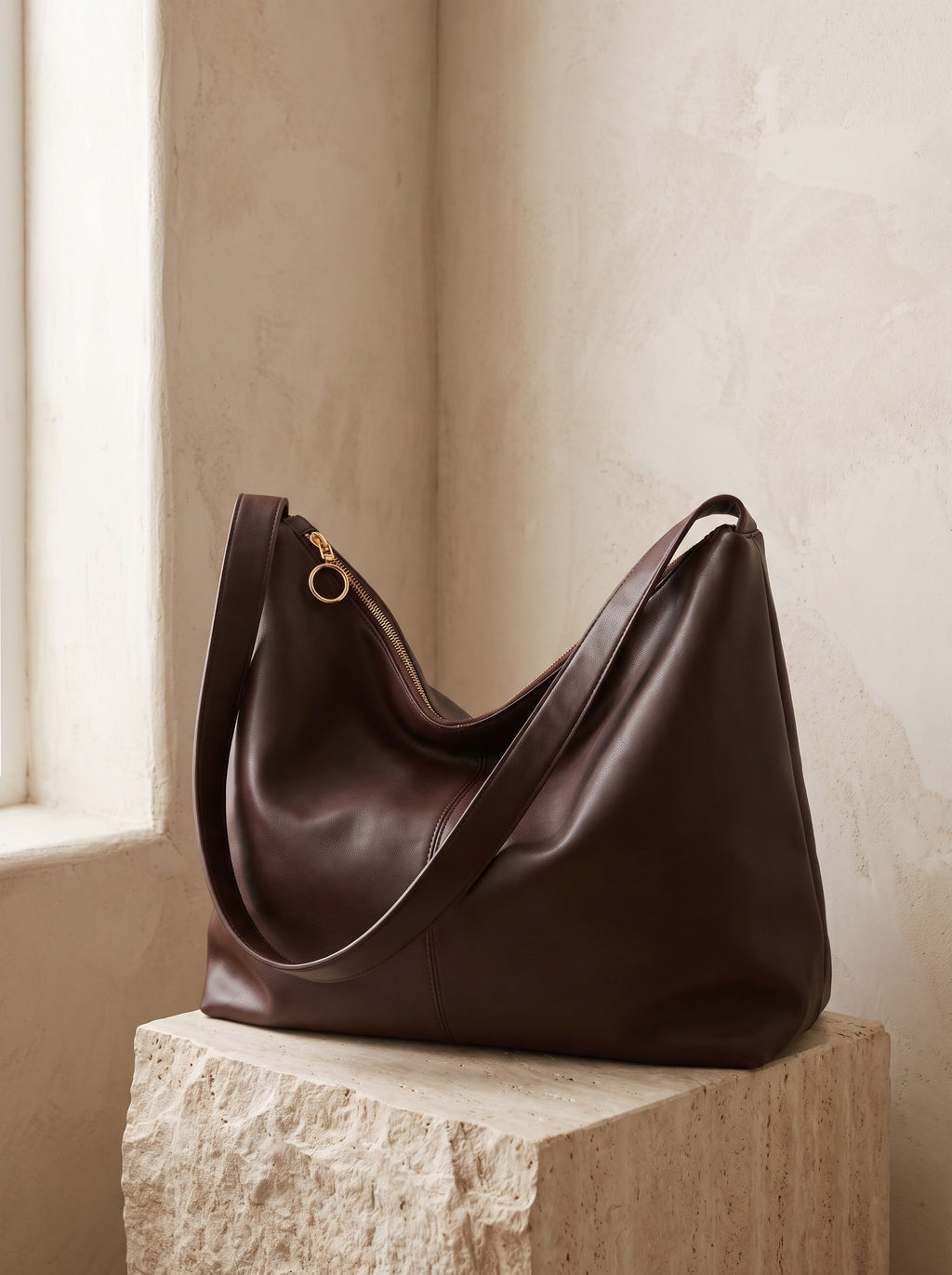 Slouch Hobo Bag in chocolate brown vegan leather resting on a travertine plinth