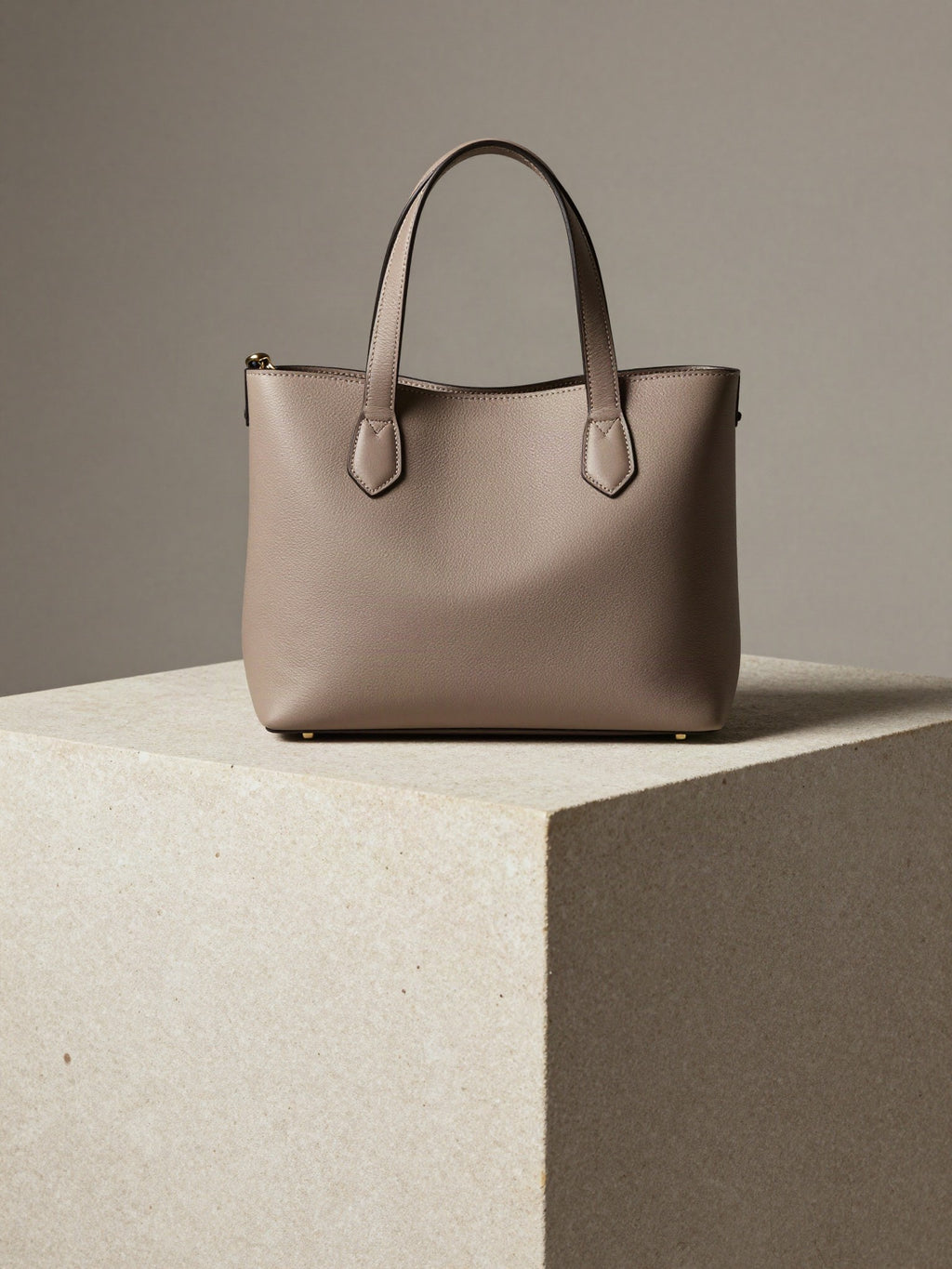 Structured Mini Tote in taupe vegan leather standing on a pale stone plinth
